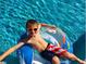 Boy enjoys the sparkling pool on a float with red-white-and-blue shorts and orange shades at 25803 Aspen Way, Golden, CO 80401