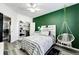 Stylish bedroom featuring green accent wall, ceiling fan, hanging chair, and walk-in closet at 5032 Nighthawk Pkwy, Brighton, CO 80601