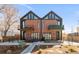 Modern townhome with a brick facade, black accents, balconies, and landscaping, under a clear blue sky at 4232 Jason St # 2, Denver, CO 80211