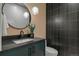 Modern powder room featuring dark vanity, round mirror, pendant lights, and stylish patterned wall at 2580 Saddleback Dr, Castle Rock, CO 80104