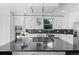 Modern kitchen featuring a black island, stainless appliances, black backsplash and sleek white cabinetry at 2745 Java Ct, Denver, CO 80211