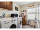 This laundry room features a front-load washer, front-load dryer, upper cabinets, and window at 14938 Vienna Cir, Parker, CO 80134