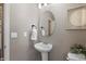 Stylish powder room with a pedestal sink, oval mirror, and decorative wall art at 7536 Grady Cir, Castle Rock, CO 80108