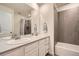 Modern bathroom featuring double vanity, large mirror, and shower-tub combination with gray tile surround at 946 Compass Dr, Erie, CO 80516