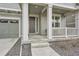 Close-up view of the covered front porch with white columns and a dark wood front door at 946 Compass Dr, Erie, CO 80516