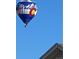 A hot air balloon with white mountain and Colorado flag designs soars above a residential neighborhood at 946 Compass Dr, Erie, CO 80516