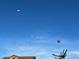 Multiple hot air balloons drift peacefully in a blue sky, creating a whimsical backdrop for the neighborhood at 946 Compass Dr, Erie, CO 80516