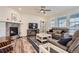 Bright living room featuring a cozy fireplace, ceiling fan, and comfortable seating area with hardwood floors at 946 Compass Dr, Erie, CO 80516