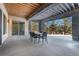 View of the covered outdoor patio with stone pillars and wooden beamed ceiling with an outdoor table and chairs at 1803 Avenida Del Sol, Castle Rock, CO 80104