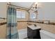 Bathroom with beige tile walls, shower-tub combination with shower curtain, vanity and mirror at 1530 W Berkeley Pl, Denver, CO 80221