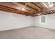 Unfinished basement with exposed wooden ceiling beams, concrete walls, and a carpeted floor at 1370 Upham St, Lakewood, CO 80214