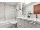 Well-lit bathroom with a double sink vanity, tub-shower combo, and neutral tile at 1370 Upham St, Lakewood, CO 80214