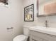 Well-lit half bathroom featuring a modern sink, vanity, and toilet with stylish wall decor at 1370 Upham St, Lakewood, CO 80214