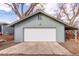 Detached garage exterior, featuring a pristine white door and durable siding, complemented by mature trees at 1370 Upham St, Lakewood, CO 80214