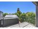 Balcony with wood flooring and black metal railing overlooks a serene, tree-lined backyard at 3057 S University Cir, Englewood, CO 80113