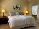 Bedroom with neutral walls, soft bedding, bedside tables with lamps, and an open doorway to the bathroom at 11014 Callaway Rd, Parker, CO 80138