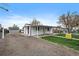 Side view of the home showcasing the gravel driveway and covered porch at 7460 Krameria Dr, Commerce City, CO 80022