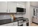 Close-up of kitchen with sleek black countertop, stainless steel appliances, and white cabinets at 937 Clarkson St # 101, Denver, CO 80218