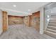 Finished basement area with gray tile flooring and exposed brick and cement wall leading to carpeted stairs at 1716 S Ogden St, Denver, CO 80210