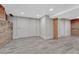 Finished basement area with gray tile flooring, white baseboards, and exposed brick and cement wall at 1716 S Ogden St, Denver, CO 80210