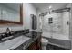 Elegant bathroom featuring marble-style tile, black granite counters, and a glass enclosed tub and shower at 26741 E Arbor Dr, Aurora, CO 80016