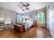 This primary bedroom features hardwood floors, ceiling fan, furnishings, a large bed, and two large bright windows at 26741 E Arbor Dr, Aurora, CO 80016