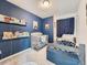 Cozy bedroom with a crib, twin bed, and book shelves against a blue accent wall at 17991 E 103Rd Ave, Commerce City, CO 80022