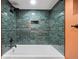 Updated bathroom showcasing blue tiled walls and tub with bronze fixtures at 1601 Albion St, Denver, CO 80220