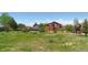 Large backyard featuring a spacious lawn, mature trees, and a charming red home at 4804 Eckert St, Castle Rock, CO 80104