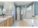 Bathroom featuring dual sinks, a tub with a shower, and serene blue walls at 4804 Eckert St, Castle Rock, CO 80104