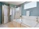 Bright bathroom with a glass shower, soaking tub, and blue textured walls at 4804 Eckert St, Castle Rock, CO 80104