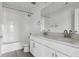 Well-lit bathroom featuring double vanity, white cabinets, and tiled shower at 25273 E Warren Pl, Aurora, CO 80018