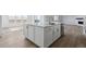 Large kitchen island with white cabinetry, sink, and stainless steel dishwasher; open floor plan to living and dining areas at 25273 E Warren Pl, Aurora, CO 80018