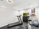 Basement with black rubber flooring contains a treadmill, flat screen TV, and stationary exercise bike at 5704 W Atlantic Pl, Lakewood, CO 80227