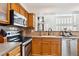 Kitchen with stainless steel appliances, wood cabinets, view to living room, and lots of counter space at 5704 W Atlantic Pl, Lakewood, CO 80227