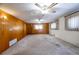 Large room featuring paneled walls, carpeted floor, and natural light from big, draped windows at 254 Donna St, Fort Lupton, CO 80621