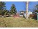 Expansive backyard with lush lawn and mature trees, a deck, and a well-maintained exterior at 7761 Everett Way, Arvada, CO 80005