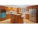 Bright kitchen with stainless steel refrigerator, custom wood cabinetry, tile countertops and backsplash, and central island at 7761 Everett Way, Arvada, CO 80005