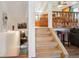 Wooden staircase leading to a bright, open-concept kitchen and dining area with natural lighting and a railing at 7761 Everett Way, Arvada, CO 80005