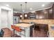 Stylish kitchen with dark wood cabinets, granite countertops, stainless appliances, and a center island with seating at 9570 Kendrick Way, Arvada, CO 80007