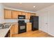 Functional kitchen with wooden cabinets, black appliances, and hardwood flooring at 400 Smith Cir, Erie, CO 80516