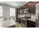 Modern kitchen featuring stainless steel appliances, a gas range, dark cabinetry, and granite countertops for style and function at 630 E Hinsdale Ave, Littleton, CO 80122
