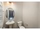 Neutral powder room features a pedestal sink, round mirror, and updated lighting at 630 E Hinsdale Ave, Littleton, CO 80122