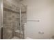 Walk-in shower featuring neutral stone tile, a glass enclosure, and convenient built-in shelving at 630 E Hinsdale Ave, Littleton, CO 80122