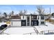 Stunning contemporary home with a combination of stone and white siding, modern windows, and a snow-covered front yard at 5258 Lions Paw St, Castle Rock, CO 80104