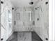 Modern glass enclosed shower with black hardware, marble-style tile, and hexagon floor at 5258 Lions Paw St, Castle Rock, CO 80104