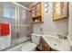 Cozy bathroom featuring a shower/tub with glass doors and a wooden vanity with ample storage at 4100 Fenton St, Denver, CO 80212