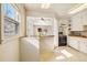 Kitchen featuring white cabinets, tiled flooring, and pass-through to the living room at 4100 Fenton St, Denver, CO 80212