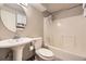 Bright bathroom featuring a pedestal sink, updated toilet, and shower over tub with curtain at 2448 S Galapago St, Denver, CO 80223