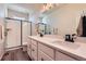 Modern bathroom featuring double sinks, white cabinetry, black fixtures, and a walk-in shower with glass doors at 24374 E 42Nd Ave, Aurora, CO 80019